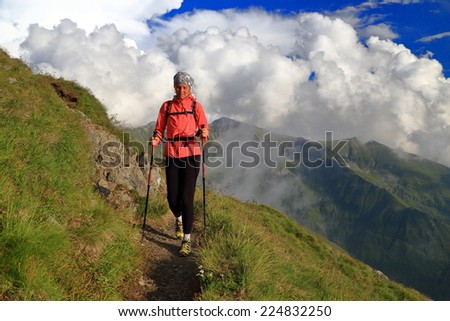 Hiker woman crossing a mountain slope on narrow trail