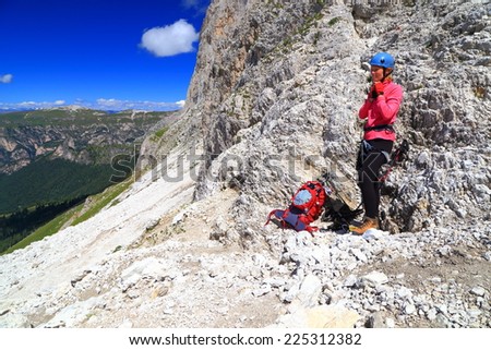 Climber woman adjusts climbing gear on \