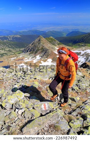 Hiker woman stepping on granite boulders on sunny morning