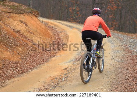 Forest road and cyclist woman pedaling on a mountain bike