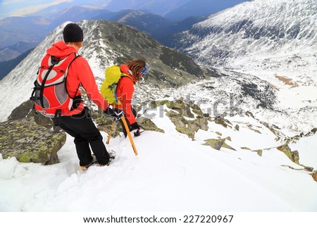 Climbers descending with the help of ice axes on snow covered slope in cloudy day