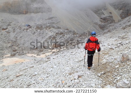 Via ferrata climber on scree covered trail above Pomedes refuge, Tofana massif, Dolomite Alps, Italy
