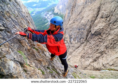 Woman clips the safety gear on the protection cable of via ferrata \