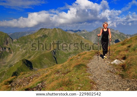 Slim woman hiker on sunny mountain trail