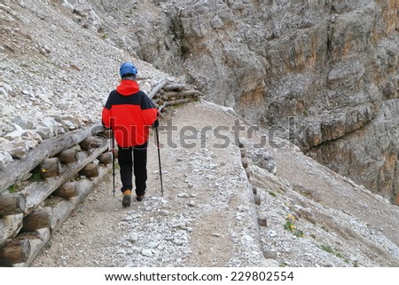 Woman climber on the road descending from Pomedes refuge, Tofana massif, Dolomite Alps, Italy