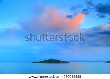 Burst of colors on the clouds above small Greek island after sunset, Corinthian gulf, Greece