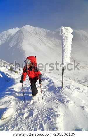 Woman mountaineer on snowy trail above the clouds