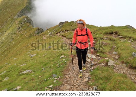 Alpine trail and fit woman hiker walking above the clouds