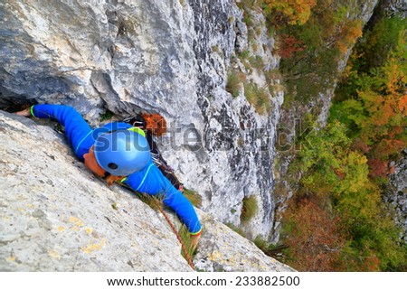 Climber woman stretching to a handhold on limestone wall