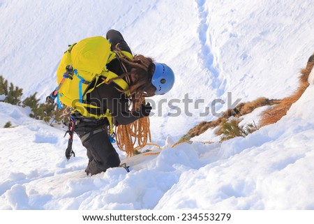Mountaineer packs the climbing rope on snowy slope
