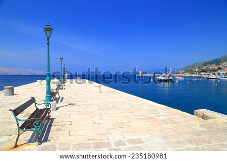Sunny stone pier with street lamps and bench by the Adriatic sea, Senj, Croatia