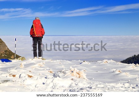 Isolated climber on a snowy trail above clouds