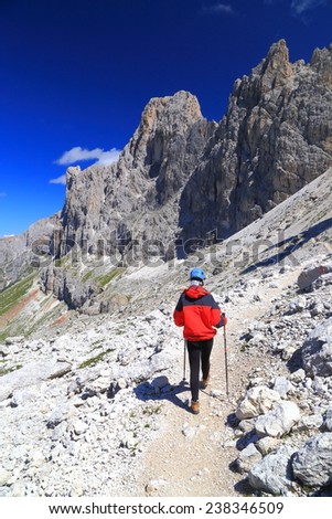 Woman climber walking on the approach trail to via ferrata route, Catinaccio massif, Dolomite Alps, Italy