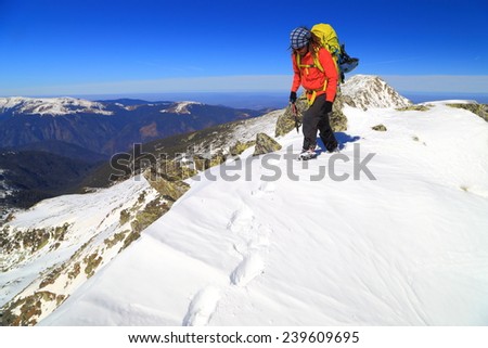 Winter mountaineer carries a backpack n snow covered summit