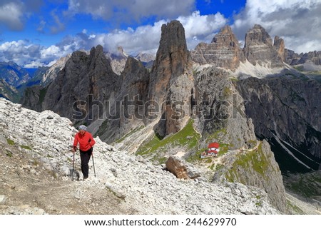 Hiker ascending a sunny trail above Savio Fonda refuge, Cadini di Misurina, Dolomite Alps, Italy