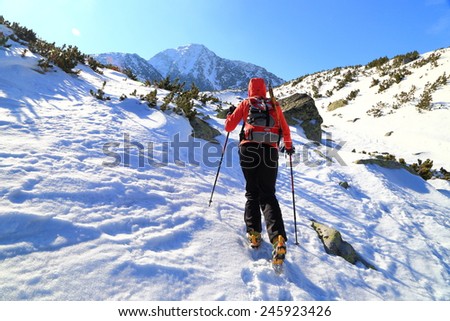 Woman climber ascending snowy trail towards distant summit