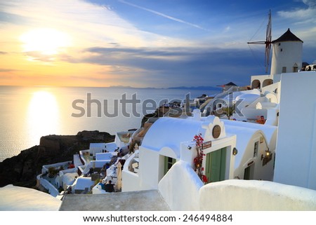 Golden light of the sunset illuminates distant sea and white buildings of Oia village, Santorini island, Greece