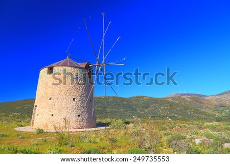 Sunny stone building of a wind mill located on green hills of Greece