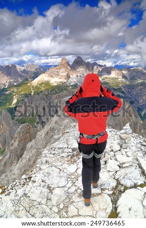 Woman climber fixing the hood while on the summit of Cima Nord Est,  Cadini di Misurina, Dolomite Alps, Italy