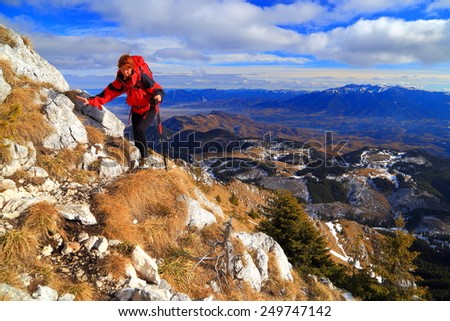 Woman hiker being tired after climbing the mountain ridge in cold autumn day