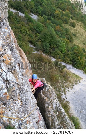 Woman climber hanging on the rock wall high above ground