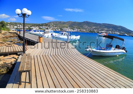Porto Rafti harbor with small boats along sunny wooden deck, Greece