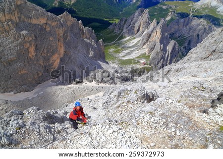Woman climber isolated on tall rock wall above the valley, Cadini di Misurina, Dolomite Alps, Italy
