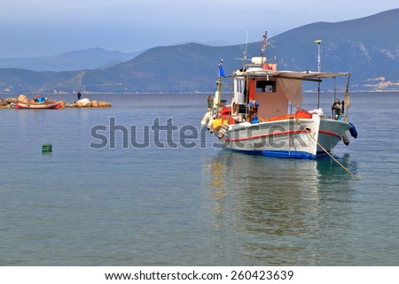 Calm water surrounding traditional wooden boat inside the harbor of Agia Kiriaki, Greece