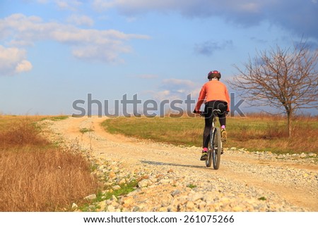 Sunny road with woman pedaling in the afternoon