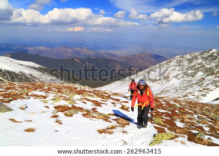 Team of hikers walking on snow covered mountain slope in sunny day of winter