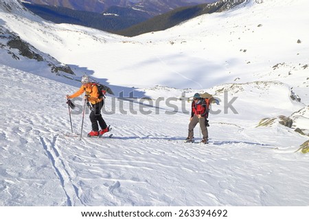 Skiers skinning uphill in sunny winter day