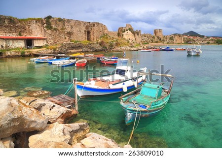 Old boats anchored on calm waters inside the Methoni harbor, Greece