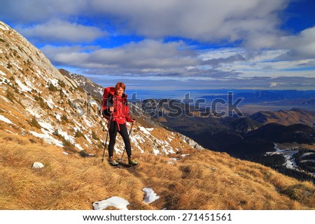 Hiker walking along grass covered trail on the mountain side