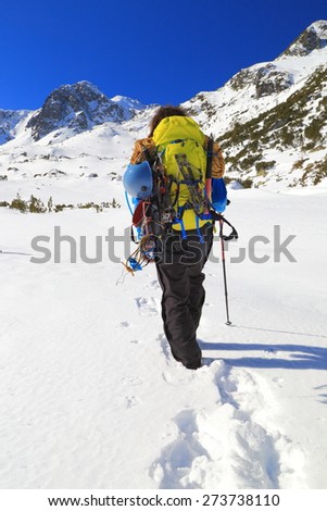 Mountain climber imprinting foot steps on deep snow in sunny day