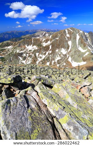 Mountain landscape with large rocks and snow spots in summer