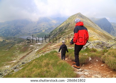 Cloudy day on the mountain with mother and son walking a narrow trail