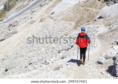 Woman climber isolated on sunny mountain trail, Catinaccio massif, Dolomite Alps, Italy