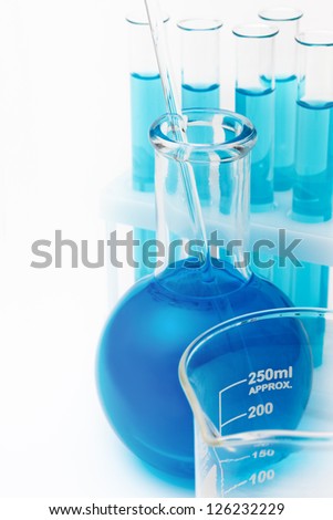 laboratory flask and test tubes with blue liquid chemical inside on white background with copy space