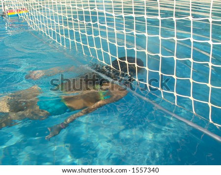 Young Girl diving under a net in a swimming-pool