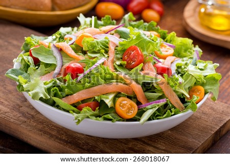 A delicious smoked salmon garden salad with smoked salmon, mixed baby greens, red and yellow cherry tomatoes and red onion with balsamic vinaigrette.