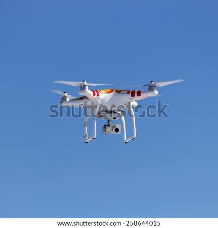 red-white quadrocopter with a video camera on the background of blue sky