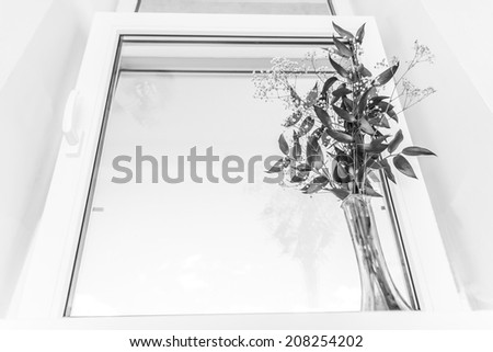 Black-and-white picture of a window with a bouquet on a window sill