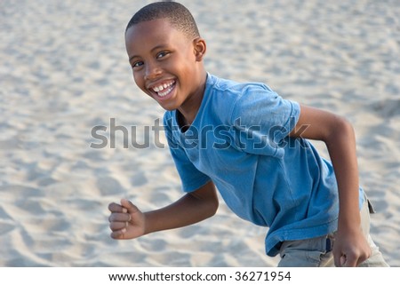 smiling happy boy has fun running at the beach, playing in sand