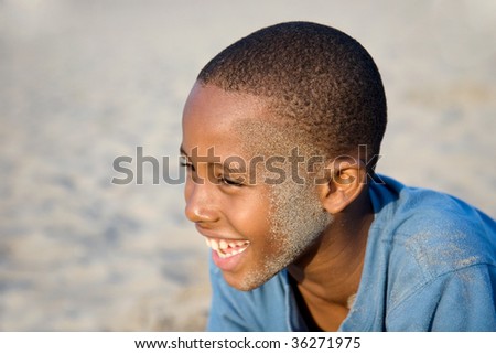smiling boy having fun wearing sand after a fall at the beach