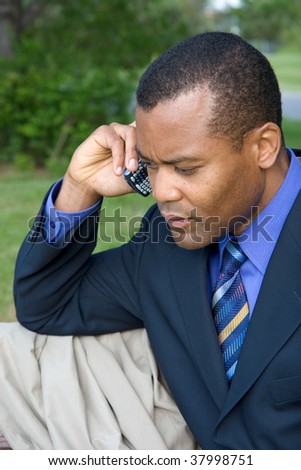 businessman on a cell phone in nature with a concerned look on his face