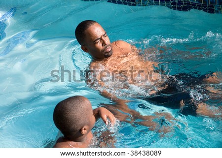 father and son swimming in the backyard pool