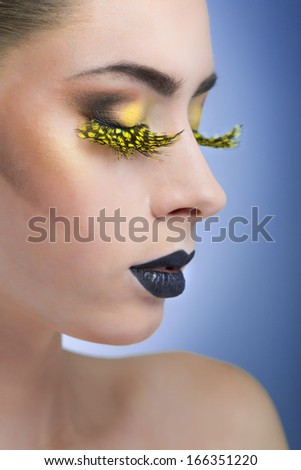 beauty woman with long yellow lashes and black lips on blue background