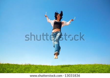 happy woman jump in field under blue sky and clouds