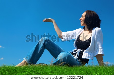 woman sit in green field un hold hand palm up