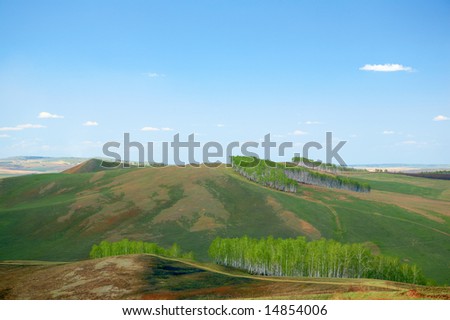 green field under blue sky with clouds